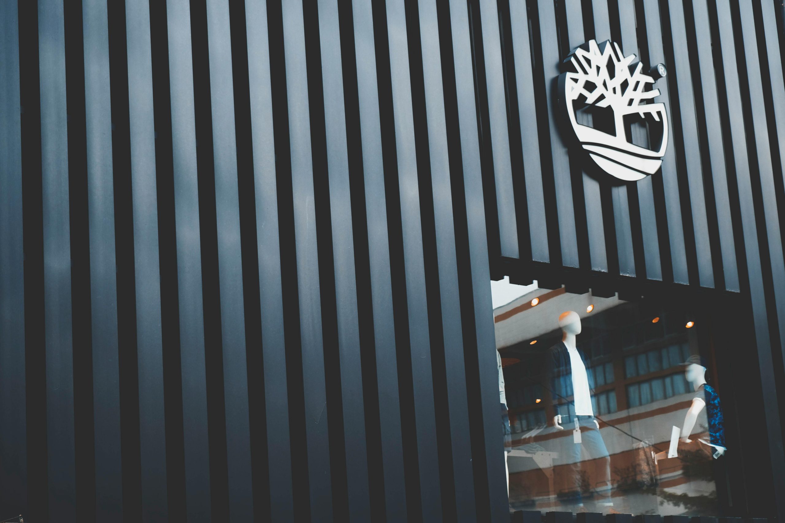 Modern storefront with displayed mannequins showcasing fashion in Taipei's urban setting.